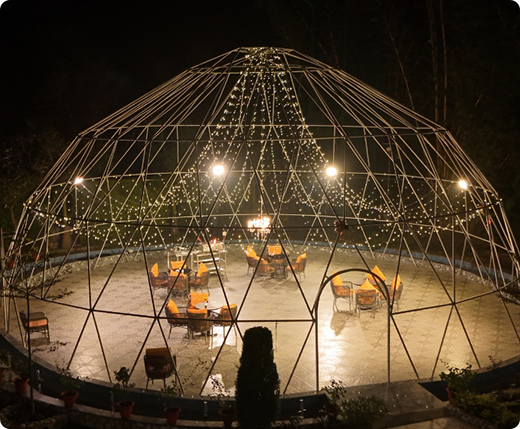 The SplitsVilla Dome glowing with warm lights under the night sky